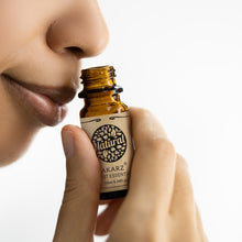 Person holding a bottle of Natural AKARZ essential oil close to their nose on a white background