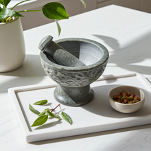 Natural soapstone mortar and pestle set with carved leaf design for crushing spices, herbs, and garlic in the kitchen.