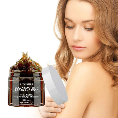 OCEAURA Black Soap with Argan and Rose woman holding jar with close-up of black soap paste on white background.