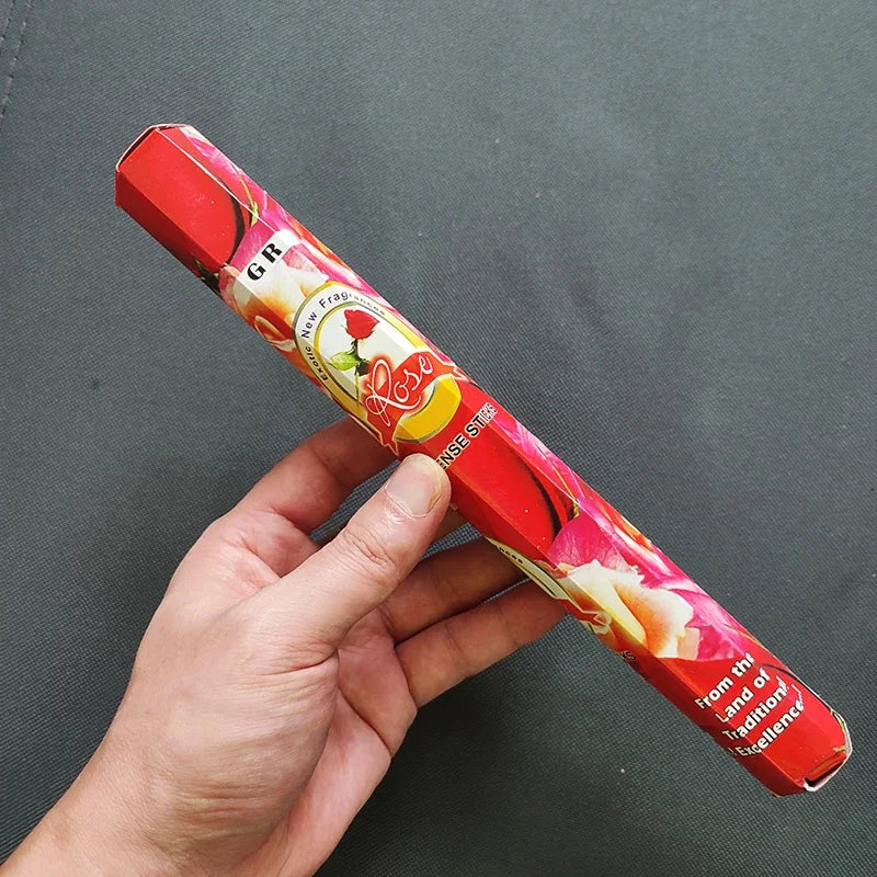 Hand holding a red and pink product packaging against a gray background