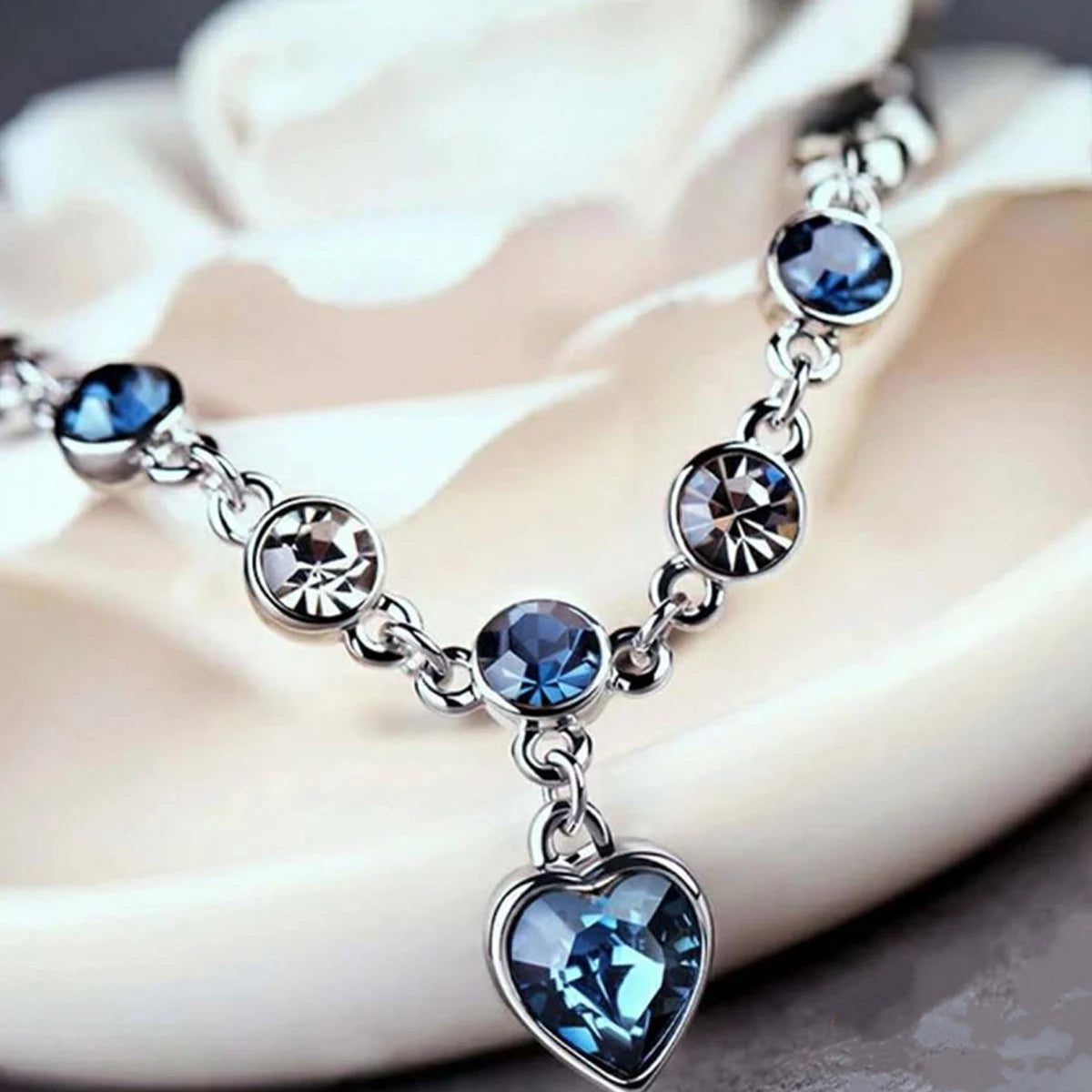 Silver bracelet with blue crystal heart charm for casual styling, special occasion wear, and fashion accessory use.