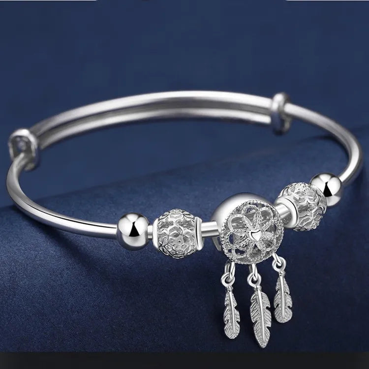 Silver feather bead dreamcatcher bangle bracelet for bohemian fashion wear and statement accessory styling.