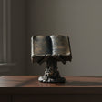 Skeleton holding spell book figurine front view for gothic home decor, altar display, and Halloween styling.