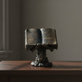 Skeleton holding spell book figurine front view for gothic home decor, altar display, and Halloween styling.