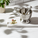 Small stainless steel mortar and pestle set for crushing spices, herbs, and garlic for cooking and food preparation.