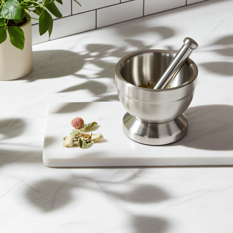 Small stainless steel mortar and pestle set for crushing spices, herbs, and garlic for cooking and food preparation.