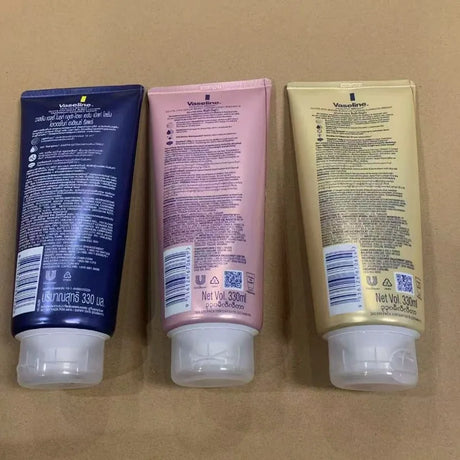 Three Vaseline Niacinamide Body Lotion 330ml tubes on a brown background.